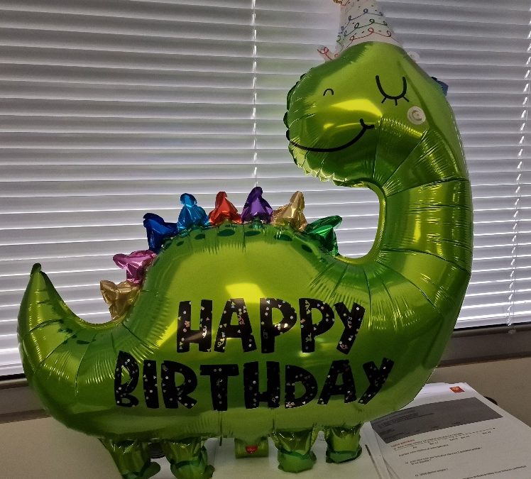 un ballon en forme de dinosaure sur lequel il est marqué "joyeux anniversaire"